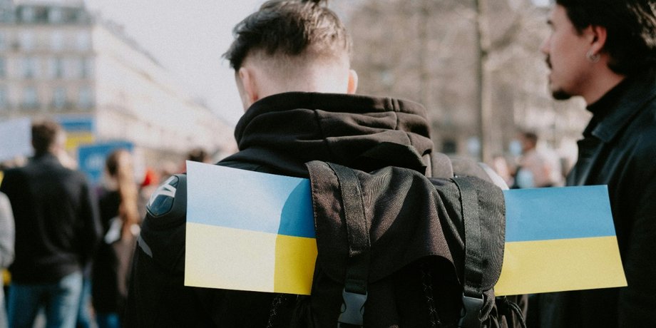 Мужчина с рюкзаком и флагом Украины в толпе
